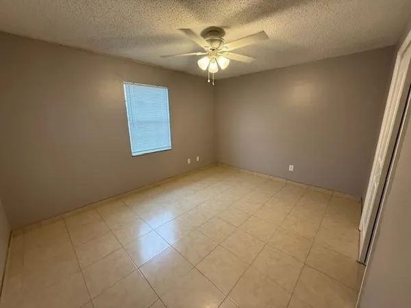 an empty room with chandelier fan and windows