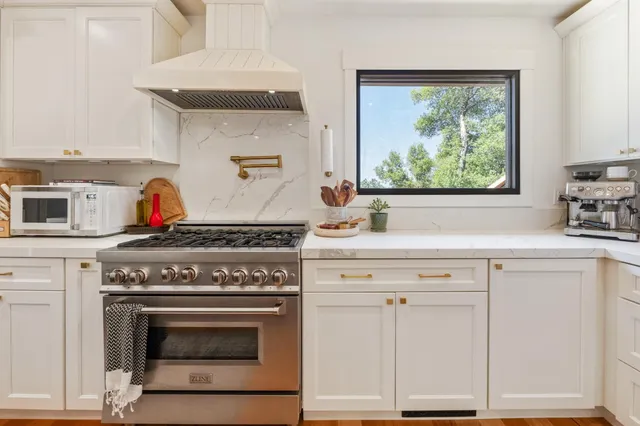 a kitchen with granite countertop white cabinets and a stove top oven
