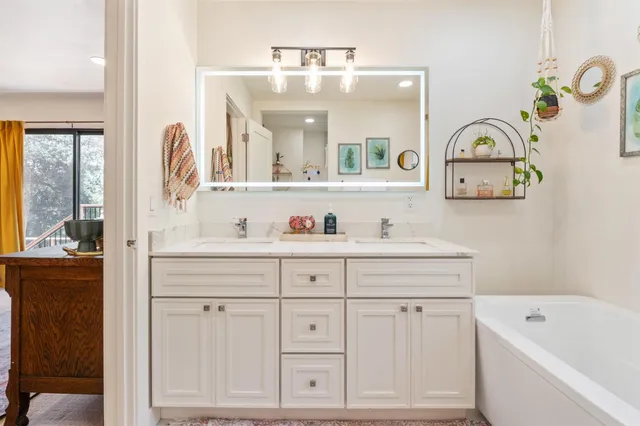 a bathroom with a sink a mirror a vanity and bathtub