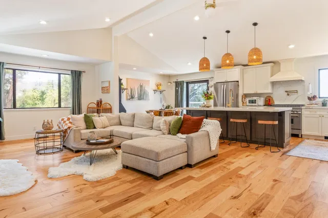 a living room with furniture kitchen area and a large window