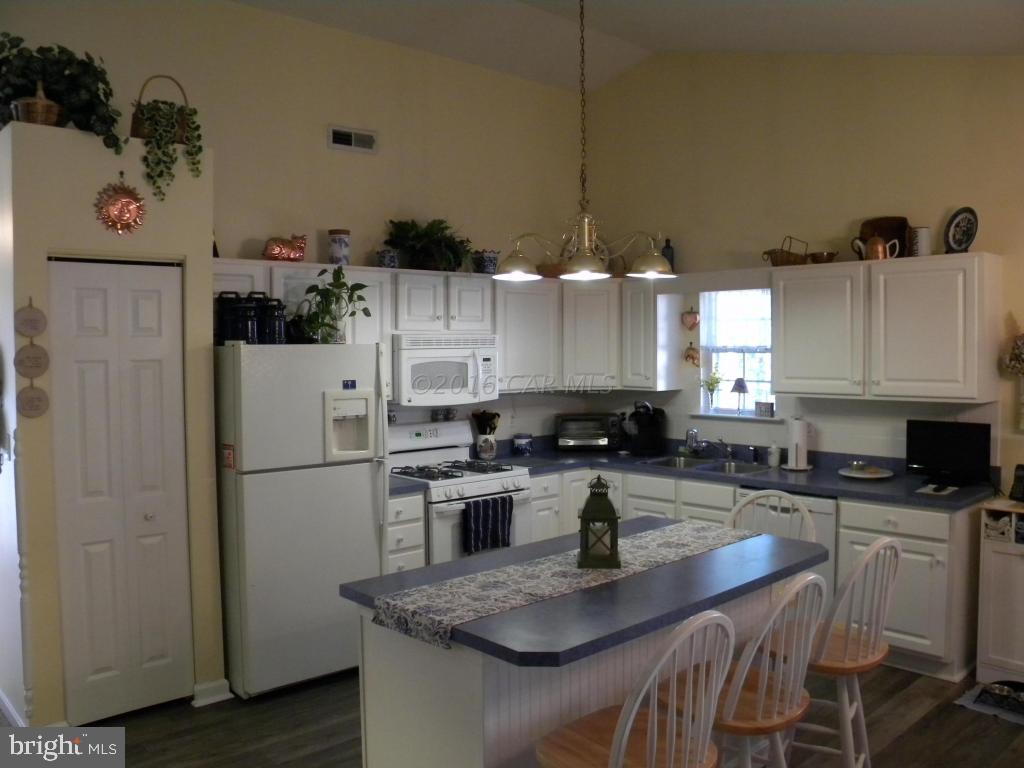 18 Falcon Bridge Road Ocean Pines, MD 21811 - Photo 4 of 21 a kitchen with a refrigerator a stove a sink dishwasher and white cabinets with wooden floor