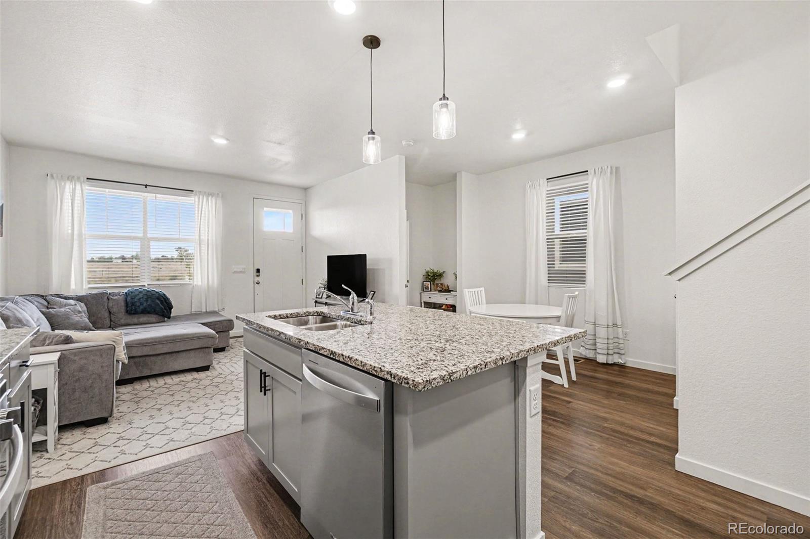 7008 Kali Court Frederick, CO 80530 - Photo 8 of 28 a view of kitchen island a sink wooden floor and a window