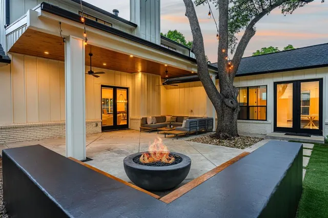 a view of a backyard with table and chairs potted plants and a large tree