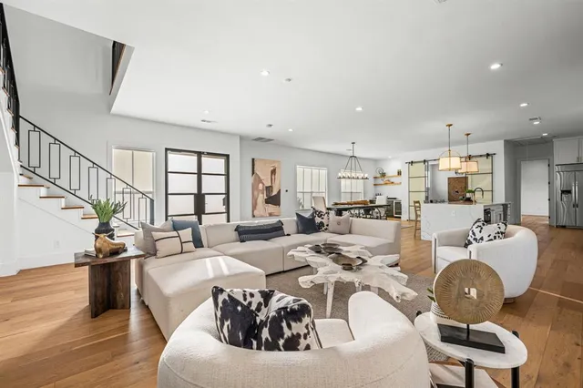 a living room with furniture kitchen view and a wooden floor