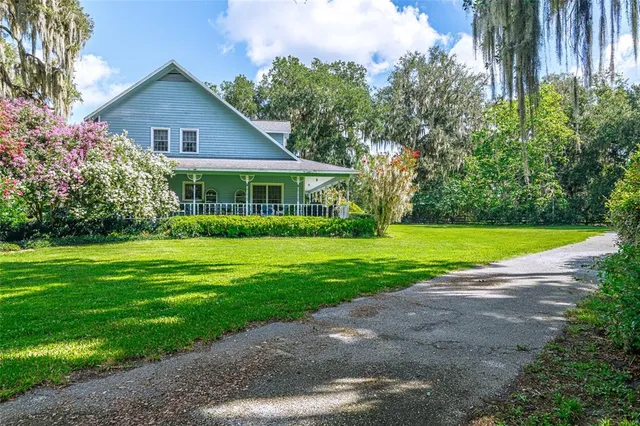a view of house with a big yard and potted plants