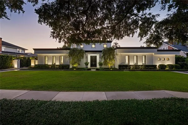 a front view of a house with a garden and trees