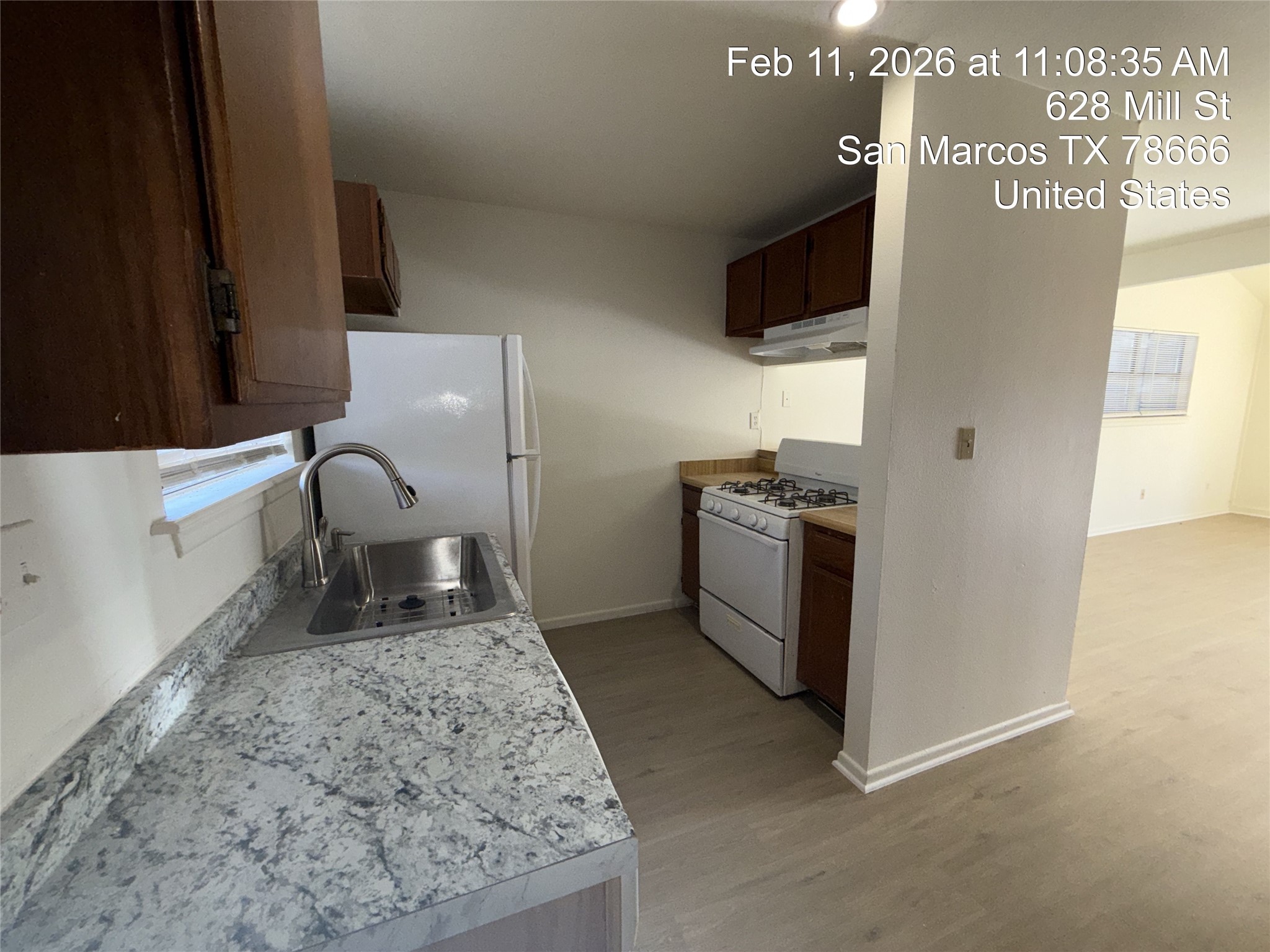 628 Mill Street, Unit B San Marcos, TX 78666 - Photo 4 of 13 Kitchen with light countertops, white appliances, light wood finished floors, and dark wood finish cabinets