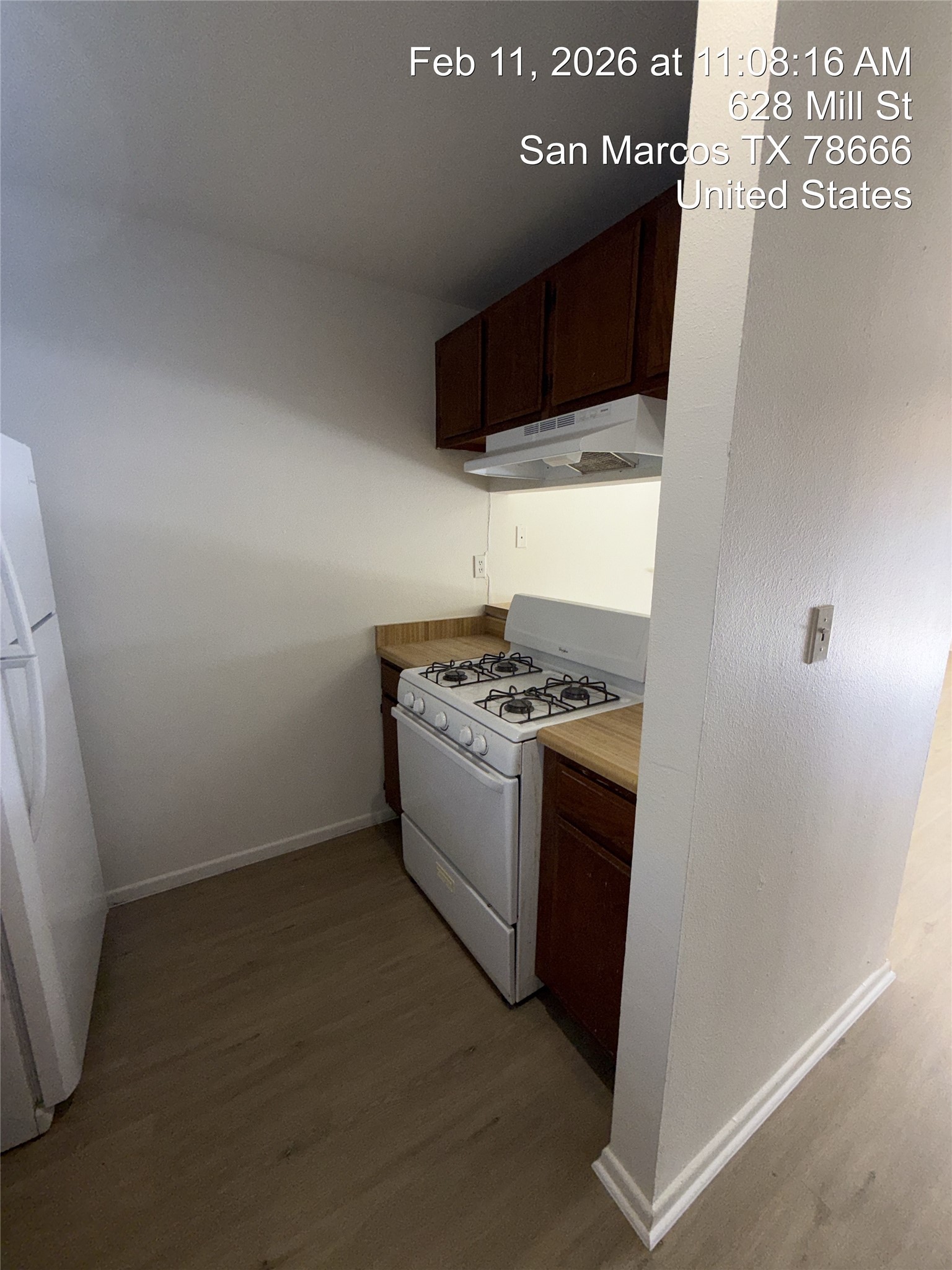 628 Mill Street, Unit B San Marcos, TX 78666 - Photo 6 of 13 Kitchen with white appliances, light wood finished floors, dark wood finish cabinetry, and light countertops