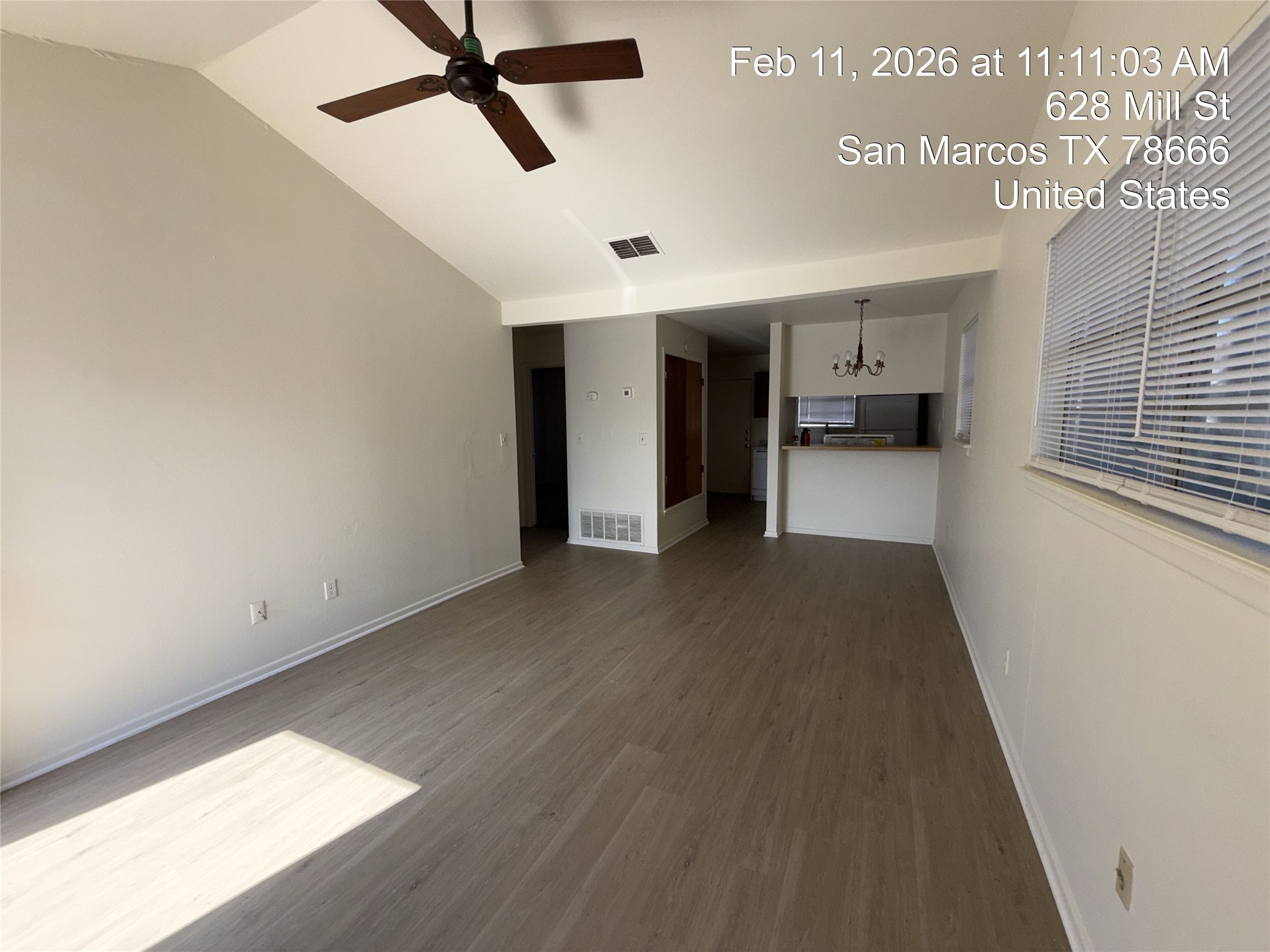 628 Mill Street, Unit B San Marcos, TX 78666 - Photo 7 of 13 Unfurnished living room with a chandelier, ceiling fan, dark wood finished floors, and a high ceiling