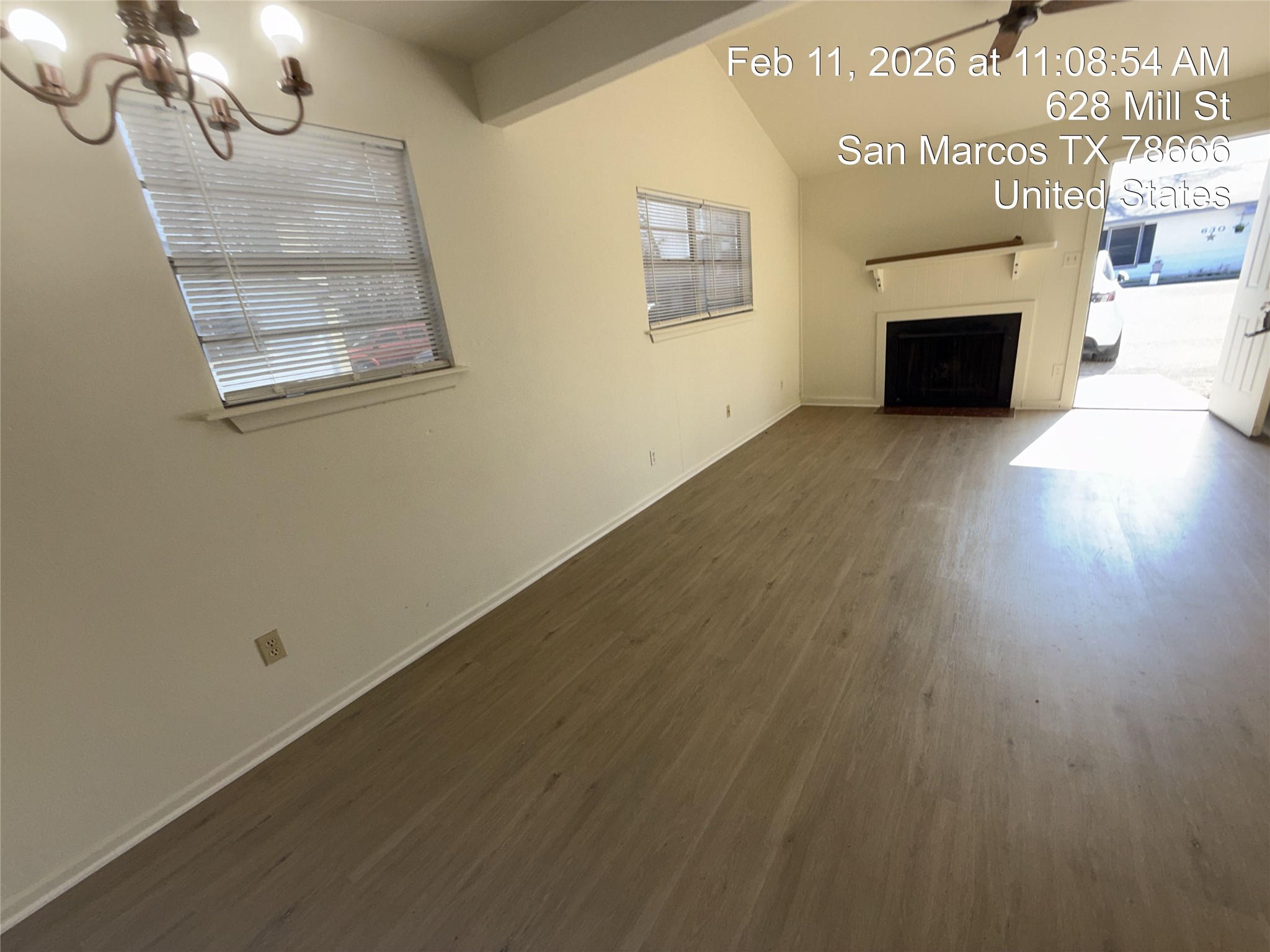 628 Mill Street, Unit B San Marcos, TX 78666 - Photo 8 of 13 Unfurnished living room with dark wood-type flooring, a fireplace with flush hearth, ceiling fan, lofted ceiling with beams, and suspended lighting