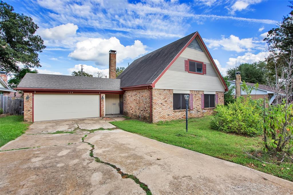 View of front of property with a shingled roof, concrete driveway, brick siding, an attached garage, and a chimney