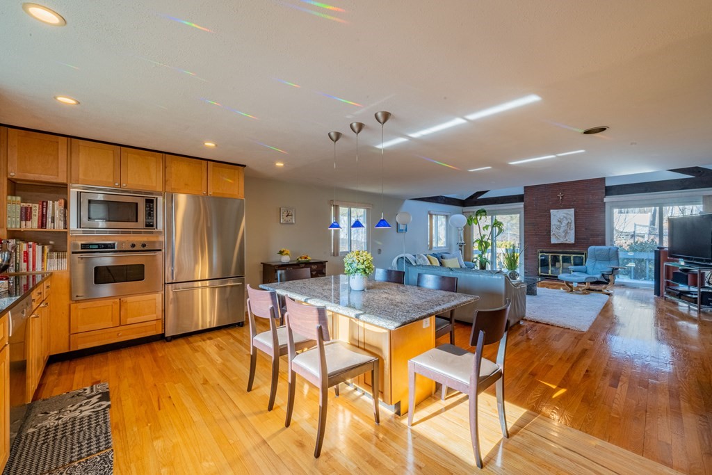 4 Springdale Road Lexington, MA 02421 - Photo 12 of 42 a kitchen with stainless steel appliances kitchen island granite countertop a refrigerator a stove a dining table and chairs with wooden floor