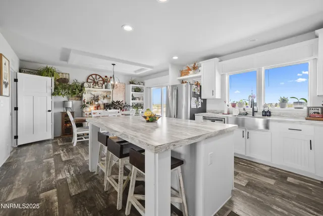 a kitchen with stainless steel appliances granite countertop a stove a sink dishwasher a refrigerator and a dining table with wooden floor