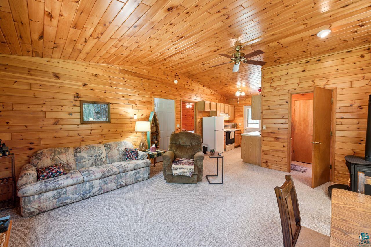 27775 Torkko Road Ashland, WI 54806 - Photo 3 of 27 Living room featuring ceiling fan, wooden ceiling, light colored carpet, and a wood stove