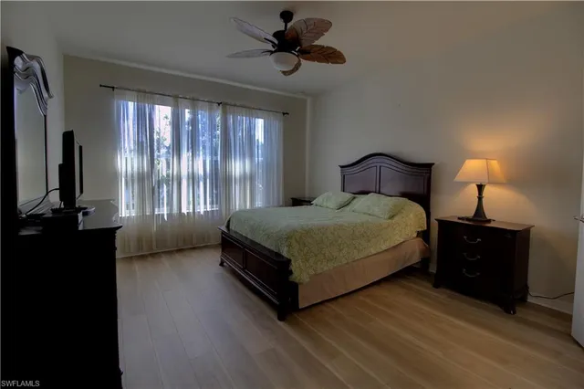 a bedroom with a bed flat screen tv and a large window
