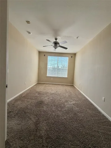 an empty room with ceiling fan and window