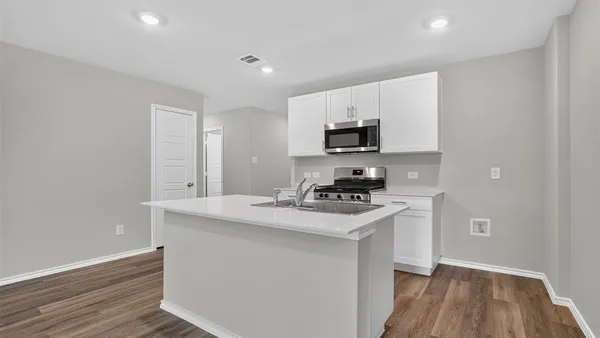 a kitchen with a sink a counter top space stainless steel appliances and cabinets