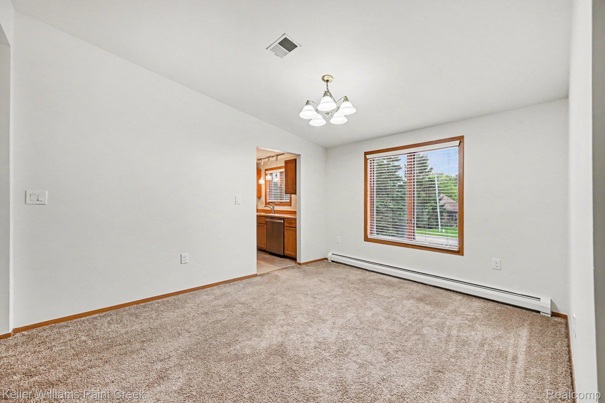 2232 London Bridge Drive Rochester, MI 48307 - Photo 9 of 26 Carpeted room with white walls, wood-trimmed window, and a chandelier