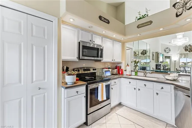 a kitchen with granite countertop white cabinets and stainless steel appliances