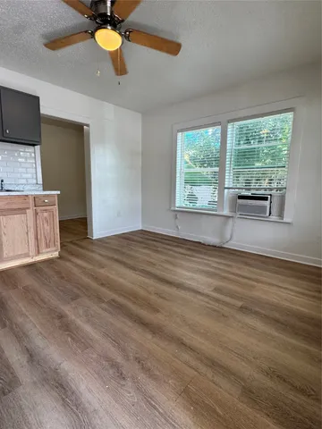a view of empty room with wooden floor and fan