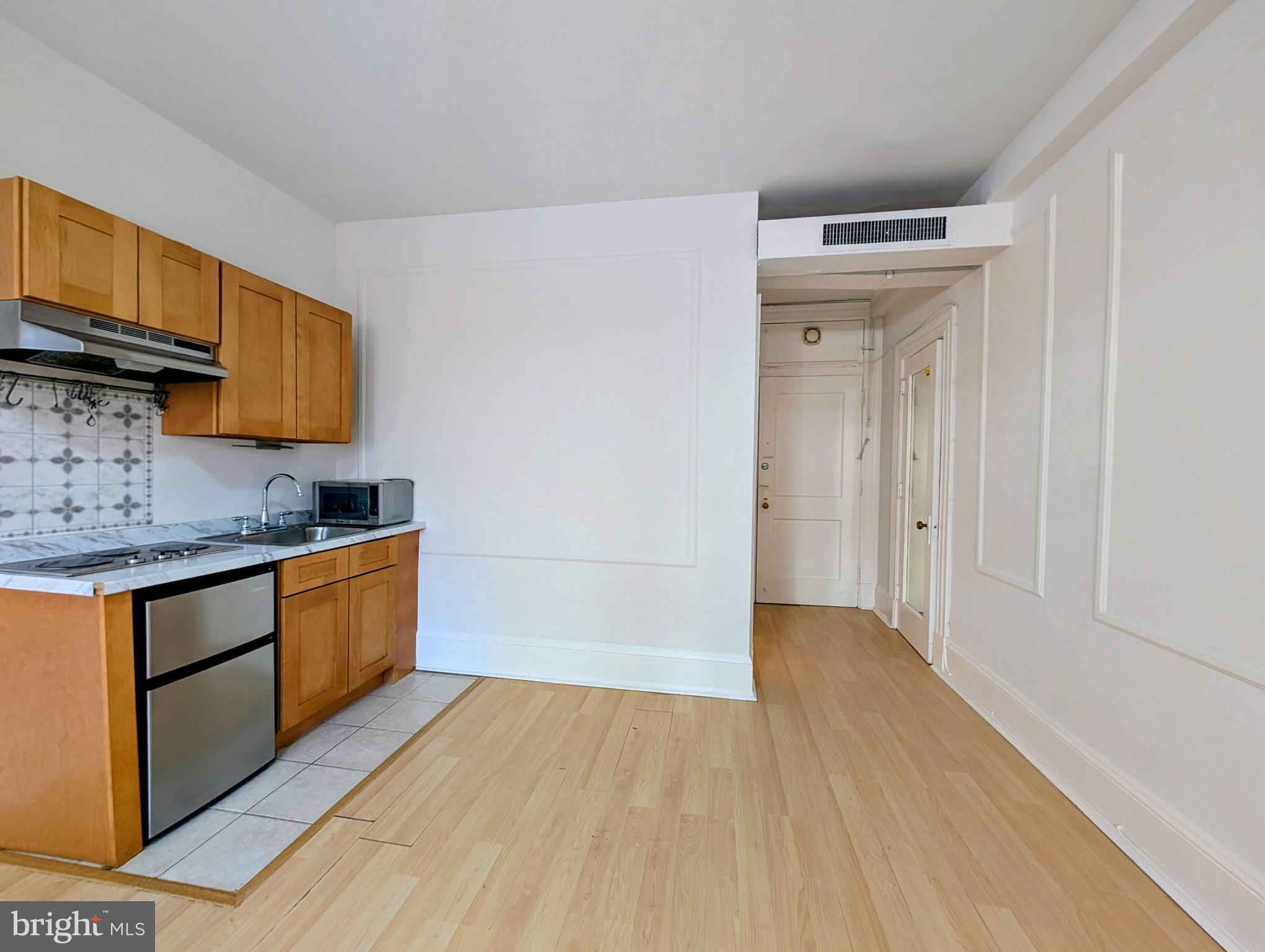 1324 Locust Street, Unit 618 Philadelphia, PA 19107 - Photo 9 of 34 a kitchen with granite countertop a sink cabinets and wooden floor