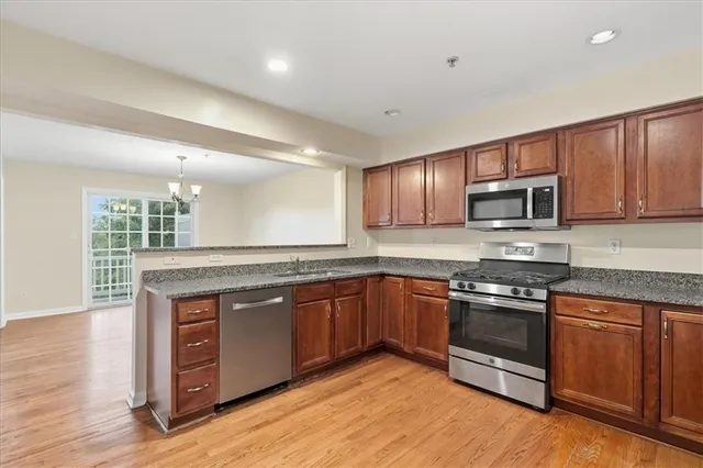 a kitchen with stainless steel appliances granite countertop wooden cabinets a sink a stove a microwave and island