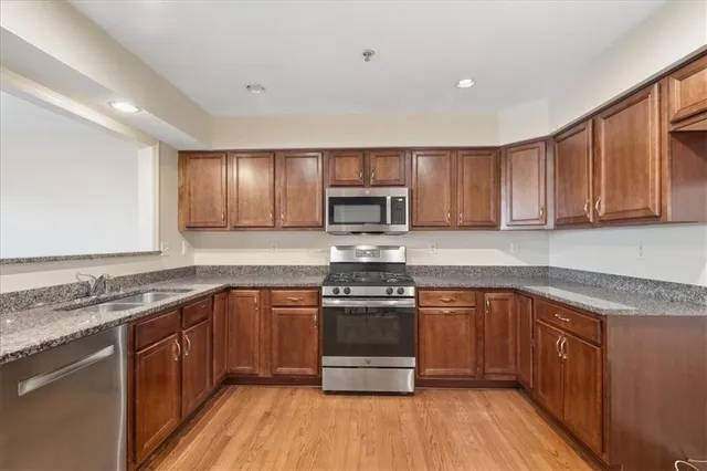 a kitchen with stainless steel appliances granite countertop wooden cabinets a stove top oven a sink and dishwasher