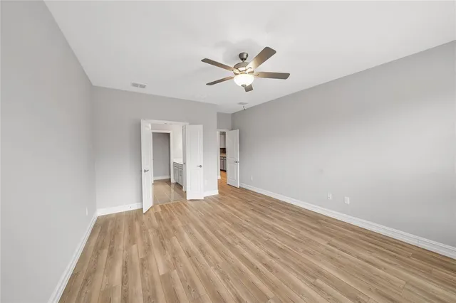 a view of empty room with wooden floor and fan