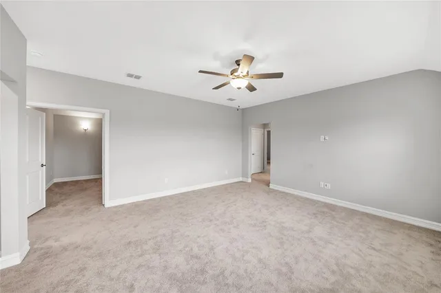 an empty room with chandelier fan and windows