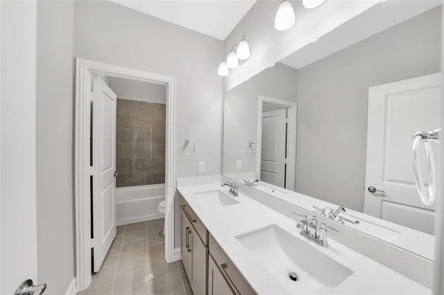 a bathroom with a tub sink double vanity and a mirror