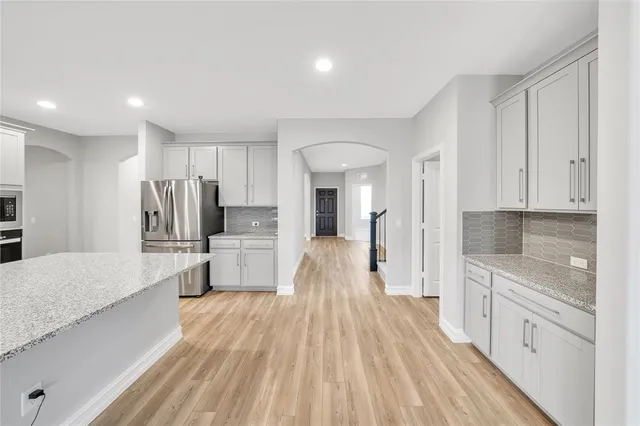 a large kitchen with kitchen island white cabinets and stainless steel appliances