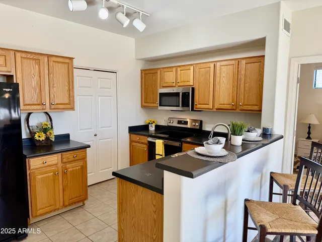 a kitchen with stainless steel appliances granite countertop a stove top oven a sink a dining table and chairs with wooden floor