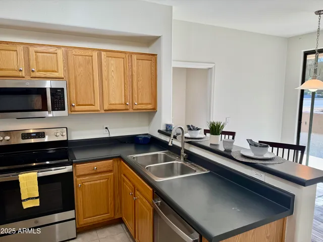 a kitchen with stainless steel appliances granite countertop a refrigerator a stove top oven a sink dishwasher and wooden cabinets