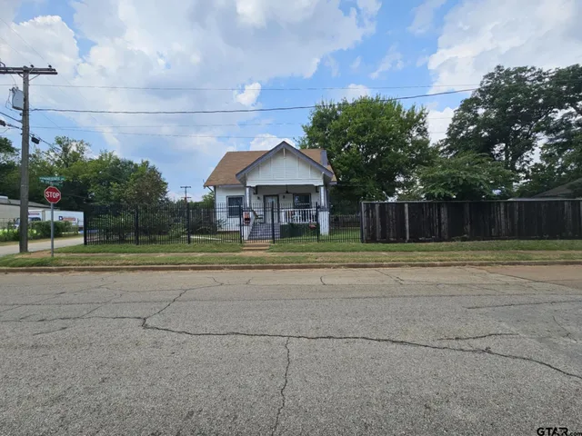 a view of a white house with a big yard and a large trees