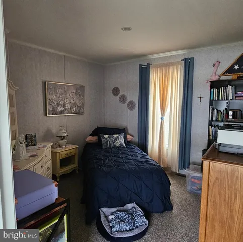 a bedroom with a bed a standing fan and a window