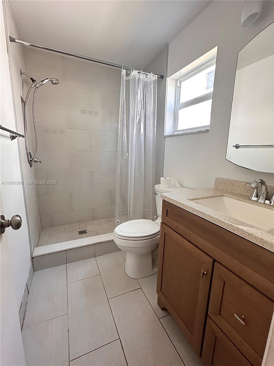 1824 Monroe Street, Unit 4 Hollywood, FL 33020 - Photo 9 of 28 a bathroom with a granite countertop sink toilet a shower and a mirror