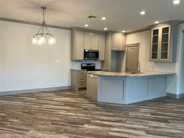 a kitchen with kitchen island granite countertop a stove a sink and a refrigerator