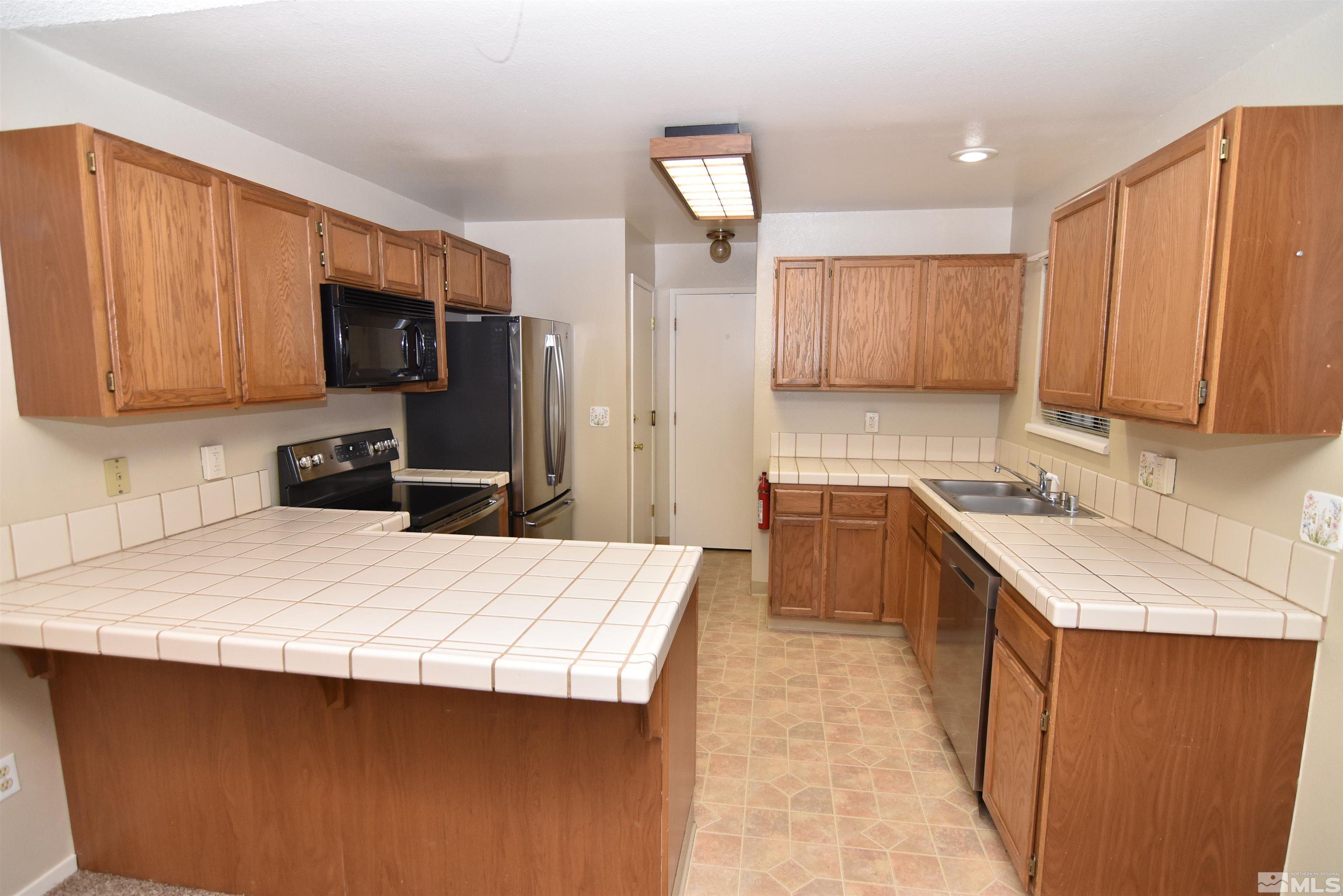 3945 Kings Row Reno, NV 89503 - Photo 4 of 19 a kitchen with kitchen island granite countertop a sink stove and refrigerator