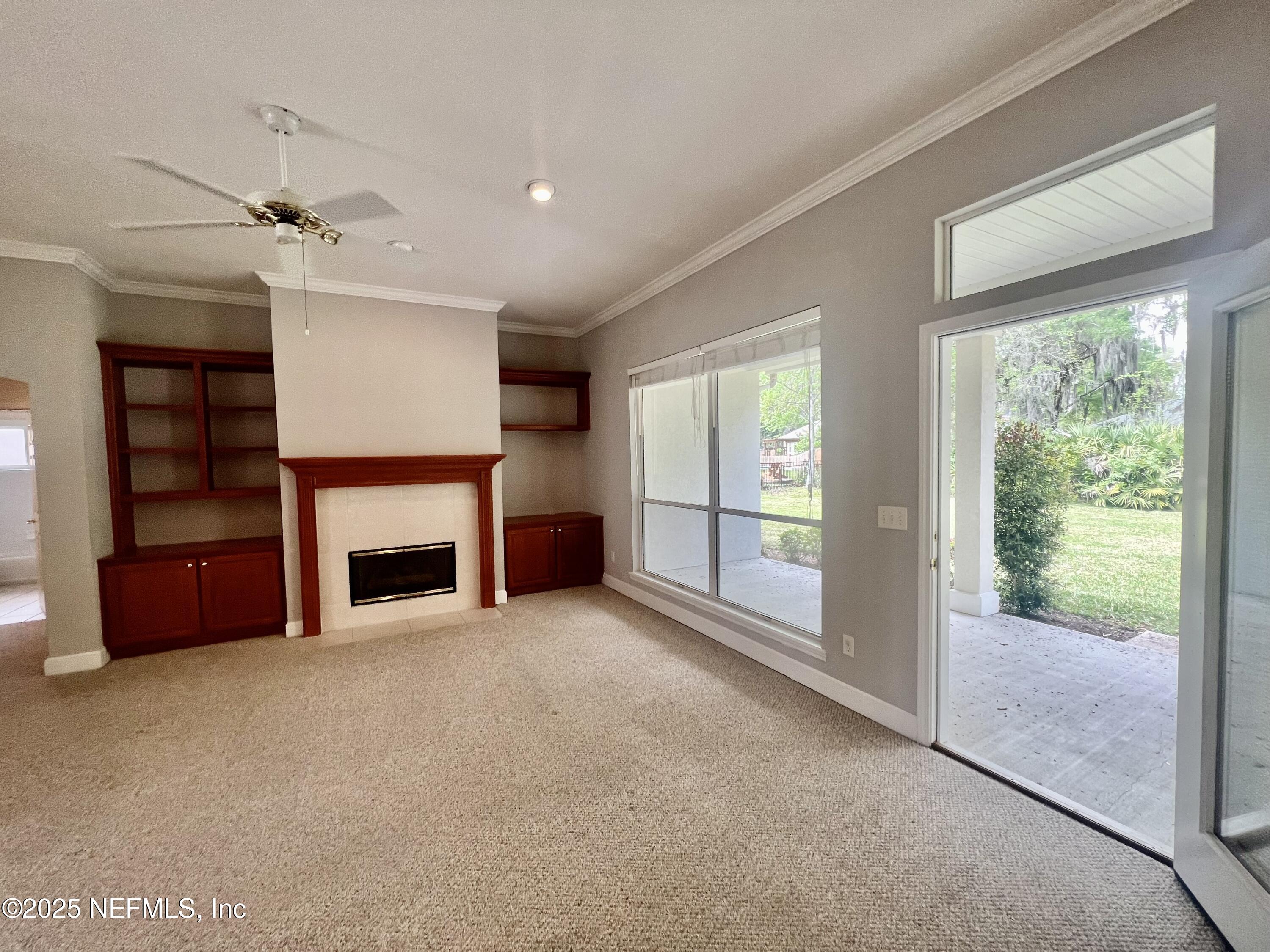 2284 Emilys Way Fleming Island, FL 32003 - Photo 15 of 36 an empty room with windows fireplace and a ceiling fan