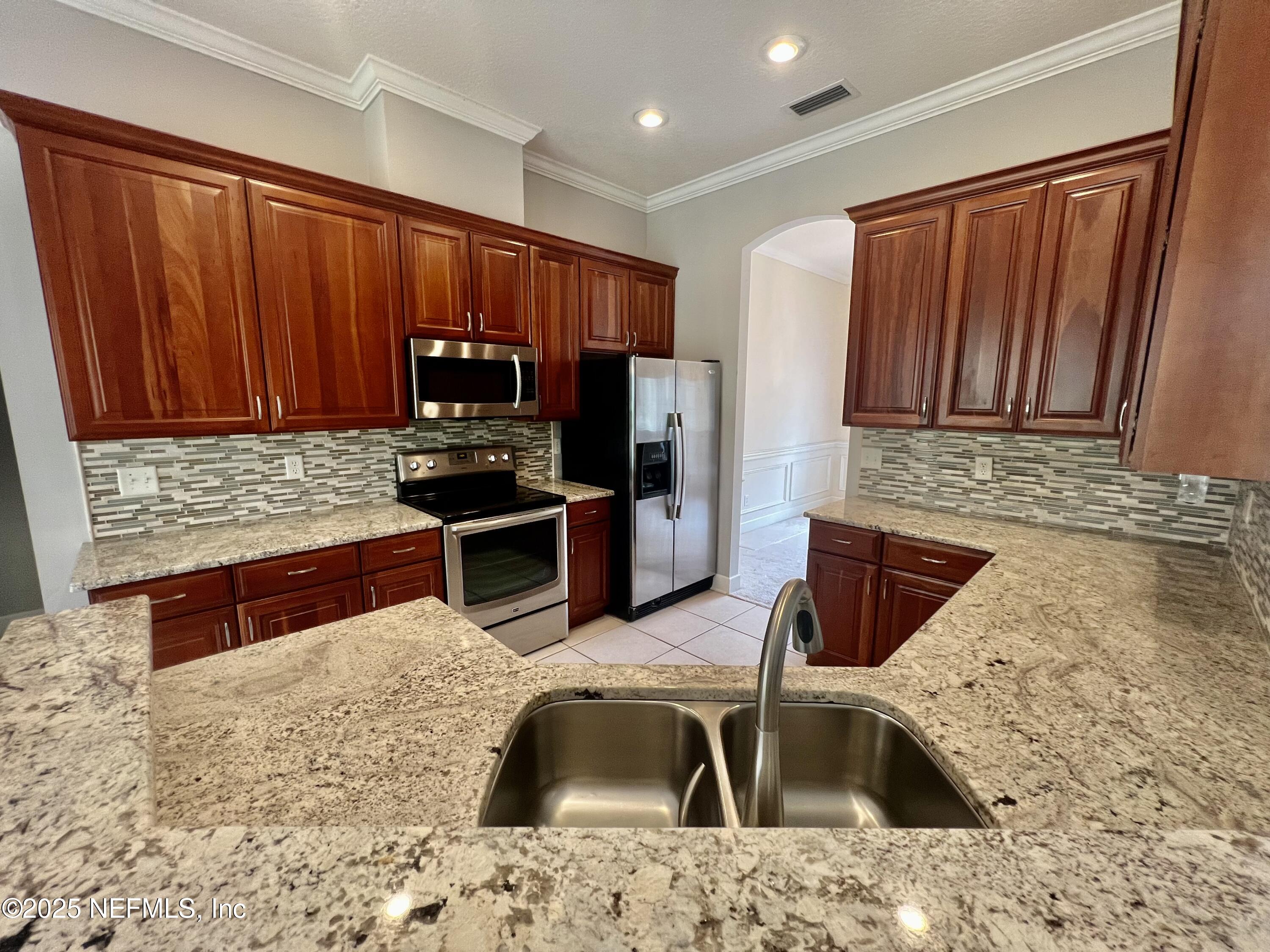 2284 Emilys Way Fleming Island, FL 32003 - Photo 6 of 36 a kitchen with stainless steel appliances wooden cabinets a sink and a granite counter tops