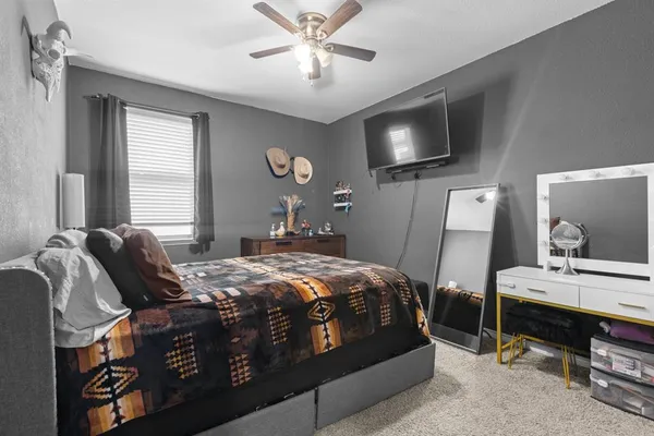 a bedroom with a bed a mirror and a flat tv screen on dresser