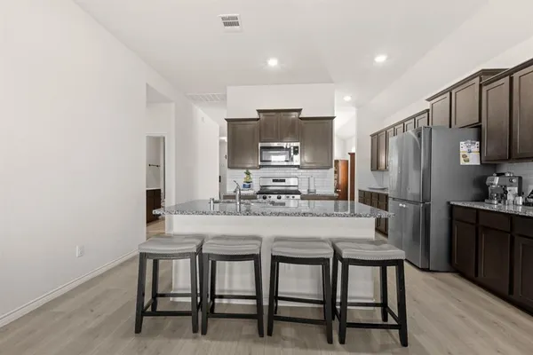 a kitchen with kitchen island a refrigerator stove microwave and cabinets