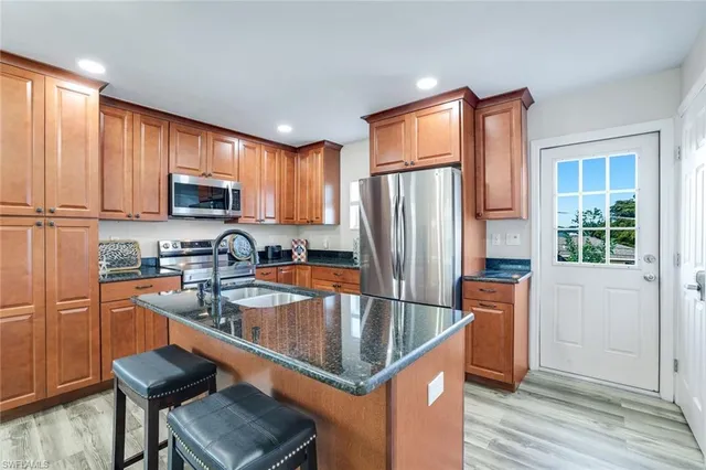 a kitchen with stainless steel appliances granite countertop a stove top oven a sink dishwasher a dining table and chairs with wooden floor