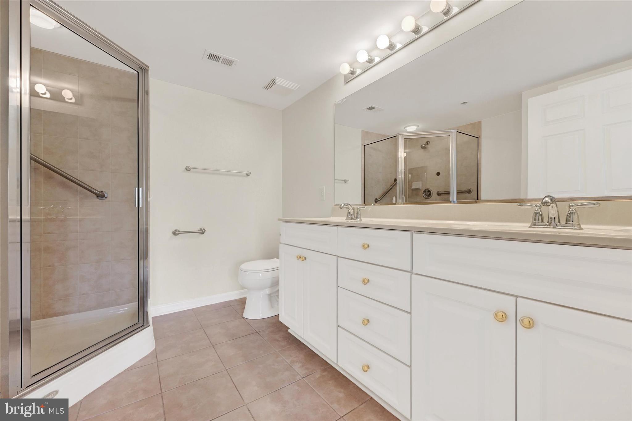 12236 Roundwood Road, Unit 104 Lutherville-Timonium, MD 21093 - Photo 23 of 27 a spacious bathroom with double sink a toilet a shower and a mirror