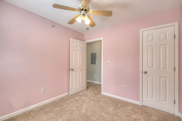 an empty room with closet and a ceiling fan