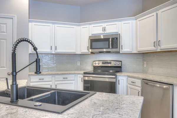 a kitchen with granite countertop a sink stainless steel appliances and cabinets