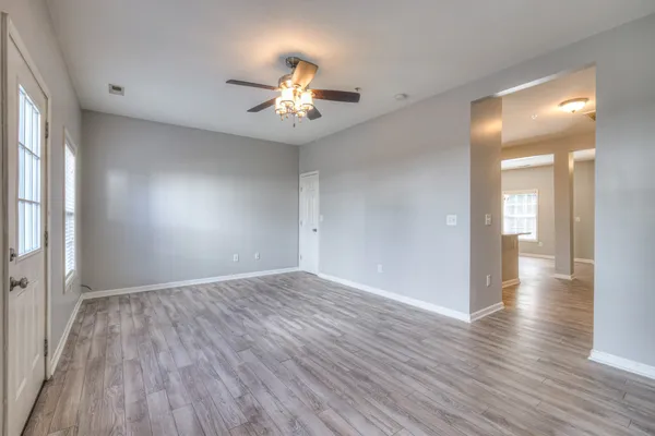 an empty room with wooden floor and windows