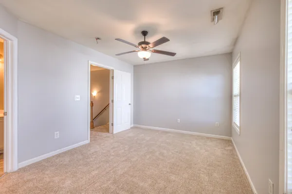 an empty room with closet and a ceiling fan