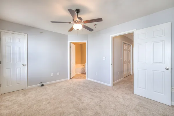 an empty room with closet and a chandelier fan