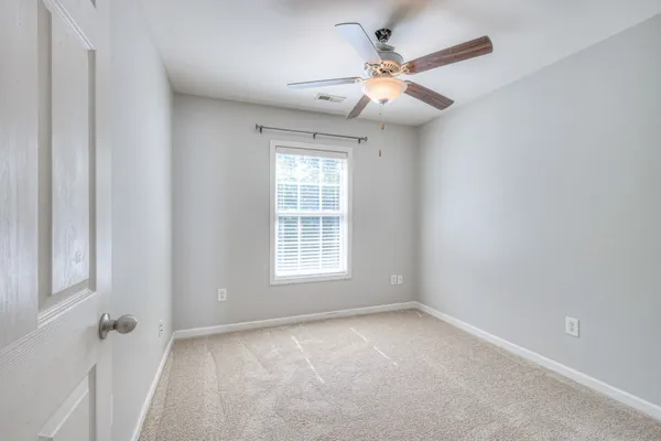 an empty room with windows and fan